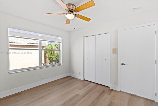 unfurnished bedroom featuring ceiling fan, light hardwood / wood-style floors, and a closet