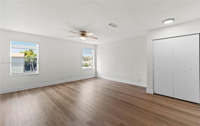 unfurnished bedroom with ceiling fan, wood-type flooring, a closet, and a textured ceiling