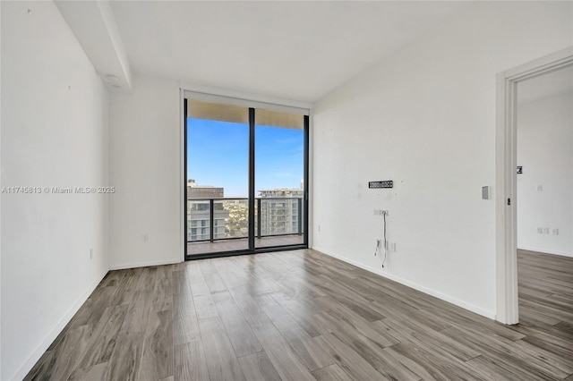 unfurnished room with hardwood / wood-style floors and expansive windows