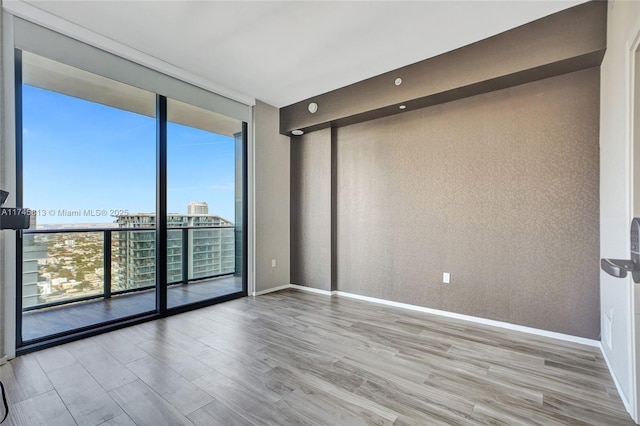 unfurnished room with a wall of windows and light wood-type flooring