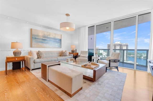 living room featuring a water view, a view of city, expansive windows, and light wood-style floors