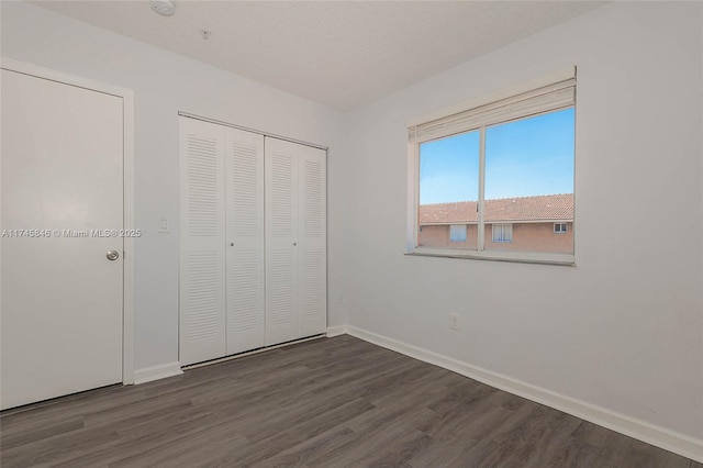 unfurnished bedroom with a textured ceiling, a closet, baseboards, and wood finished floors