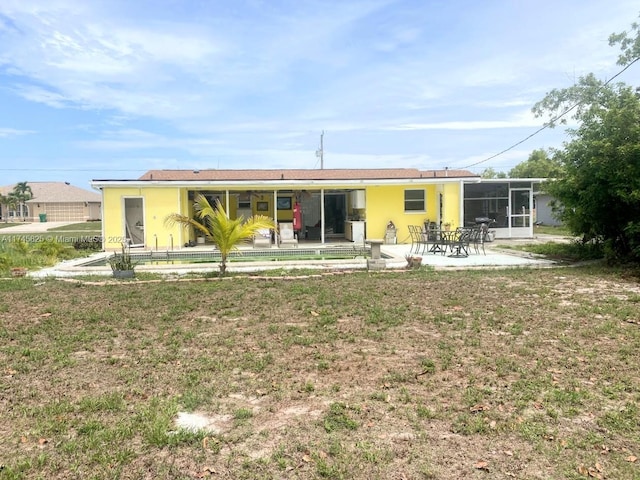 back of property with a lawn, a sunroom, and a patio