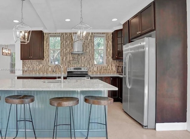 kitchen with an inviting chandelier, stainless steel appliances, light stone countertops, and a center island with sink