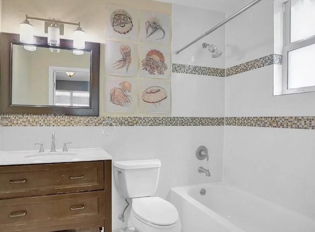 full bathroom featuring tiled shower / bath combo, vanity, tile walls, and toilet