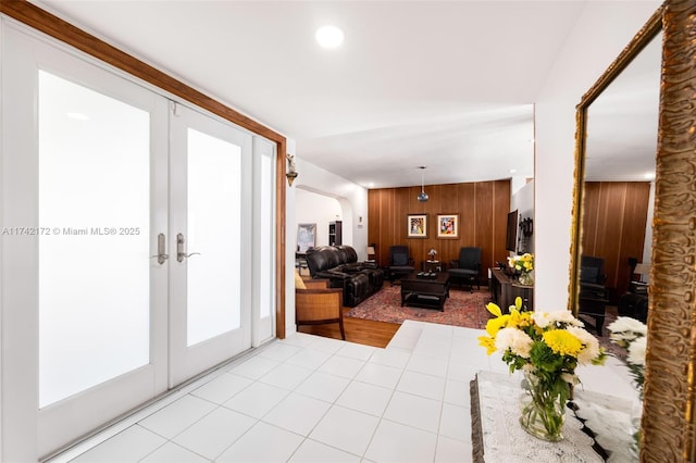 interior space with wooden walls, french doors, and light tile patterned flooring