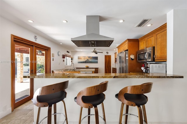 kitchen with french doors, sink, appliances with stainless steel finishes, kitchen peninsula, and island exhaust hood