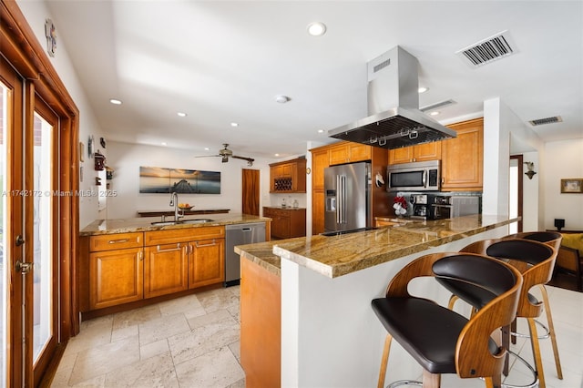 kitchen with island range hood, stainless steel appliances, kitchen peninsula, and a kitchen breakfast bar