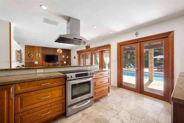 kitchen with pendant lighting, electric range, island range hood, kitchen peninsula, and french doors