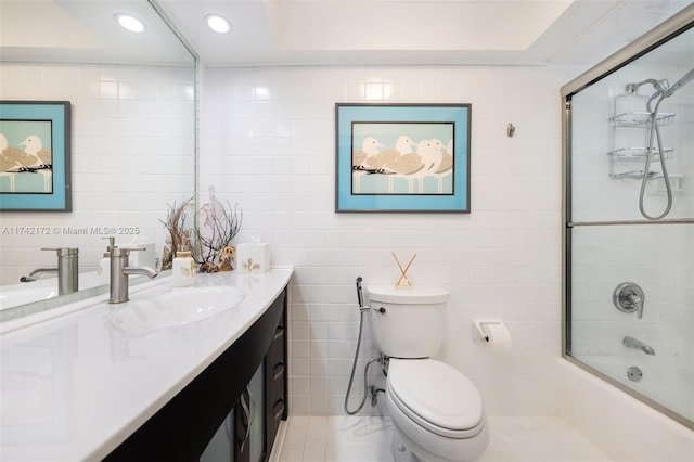 full bathroom with vanity, toilet, combined bath / shower with glass door, and tile walls