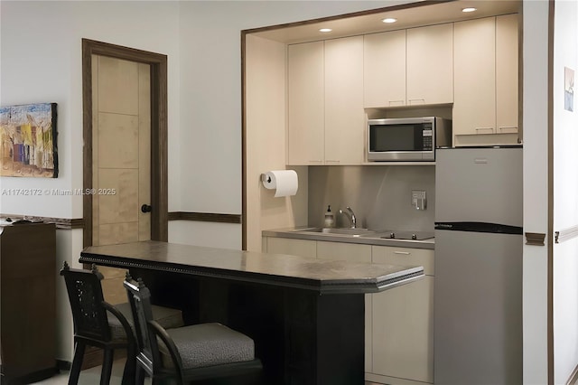 kitchen featuring sink, white cabinetry, a kitchen breakfast bar, stainless steel appliances, and kitchen peninsula