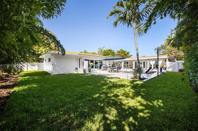 rear view of house featuring a lawn and a patio area