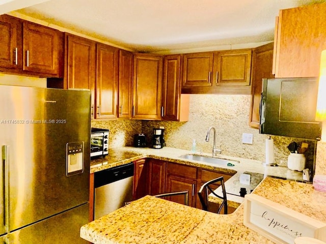 kitchen with tasteful backsplash, appliances with stainless steel finishes, sink, and light stone counters