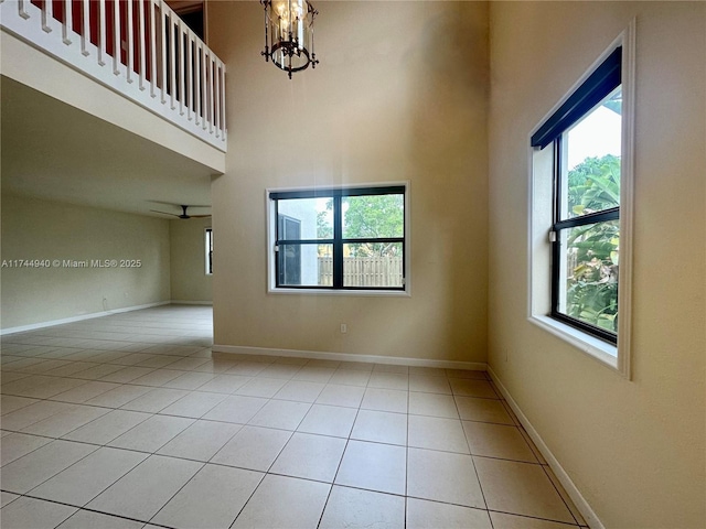 unfurnished room featuring a towering ceiling, light tile patterned floors, and an inviting chandelier