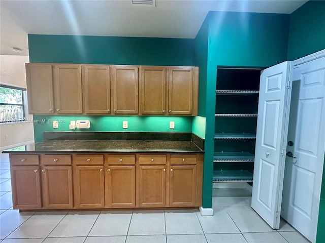 kitchen with light tile patterned flooring and dark stone counters