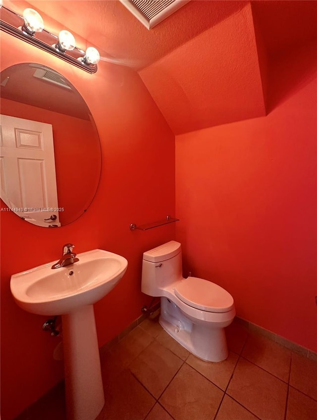 bathroom featuring lofted ceiling, a textured ceiling, tile patterned floors, and toilet