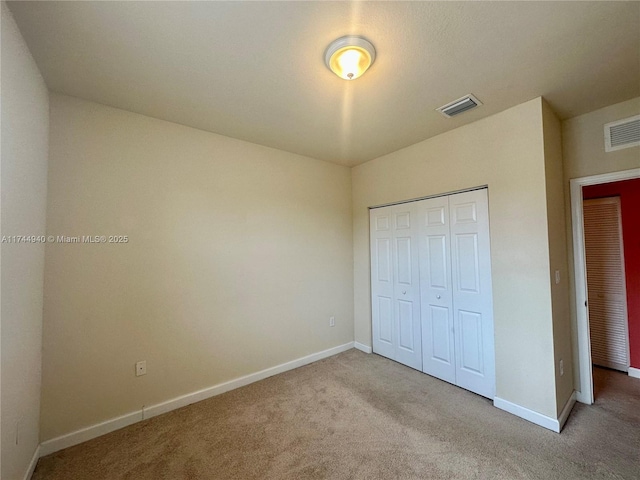 unfurnished bedroom with light colored carpet and a closet