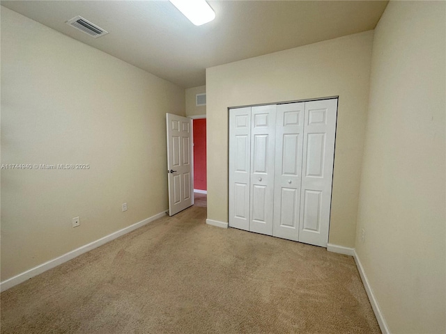 unfurnished bedroom with light carpet and a closet