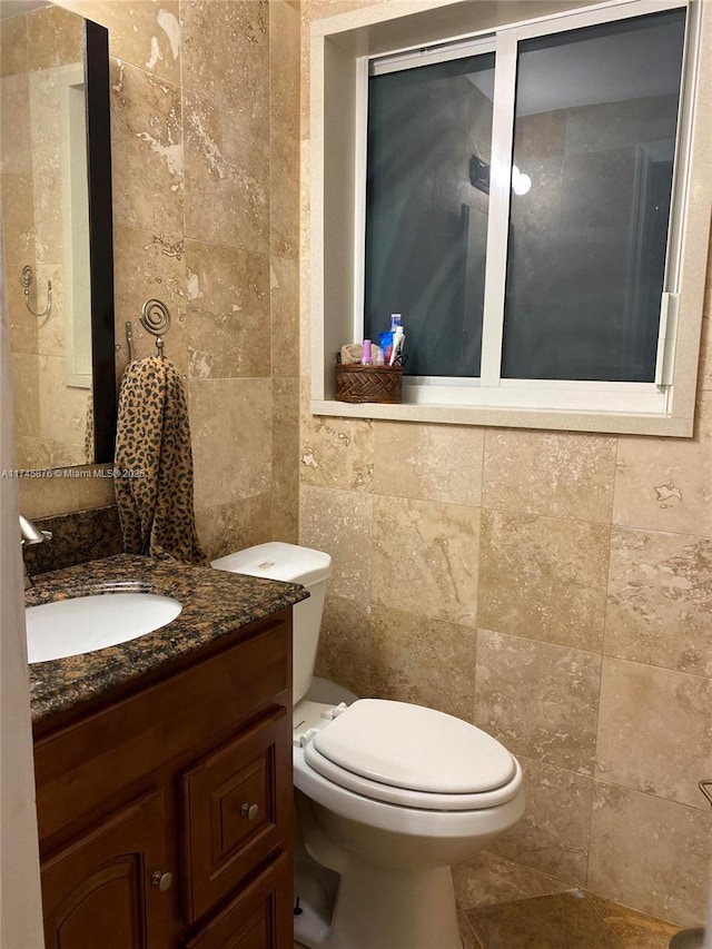 bathroom with tile walls, toilet, and vanity