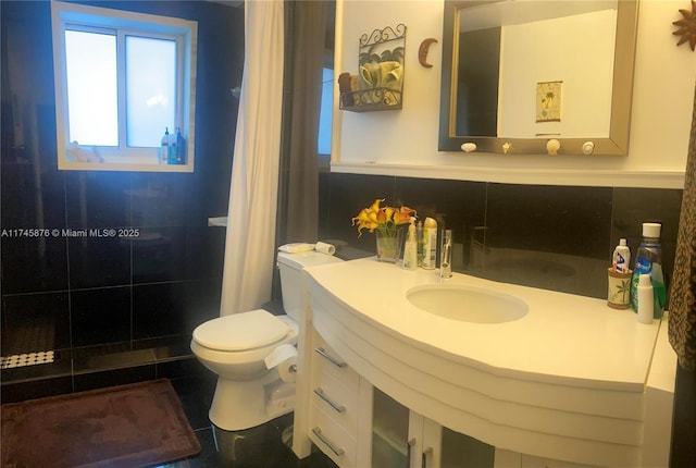 bathroom featuring toilet, vanity, and tiled shower