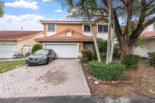 view of front facade featuring a garage, decorative driveway, a tile roof, and stucco siding