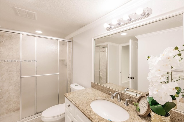 bathroom featuring vanity, toilet, a shower with door, and a textured ceiling