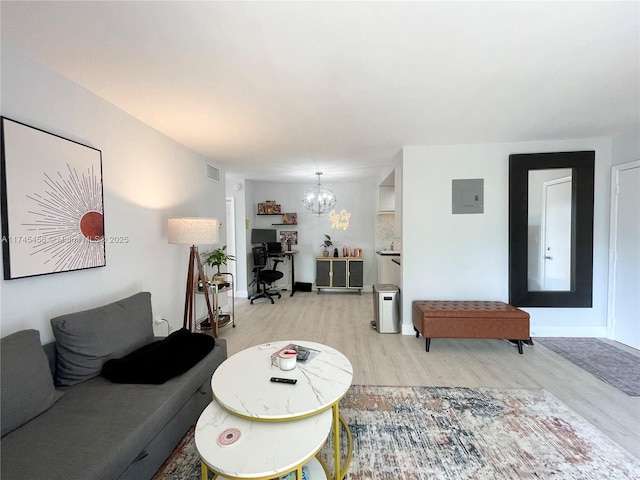 living room with a notable chandelier, electric panel, and light wood-type flooring