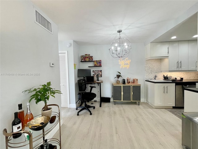 kitchen featuring tasteful backsplash, decorative light fixtures, light hardwood / wood-style flooring, dishwasher, and white cabinets