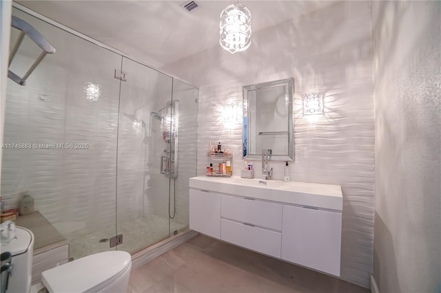 bathroom featuring vanity, toilet, tile walls, and a shower with shower door