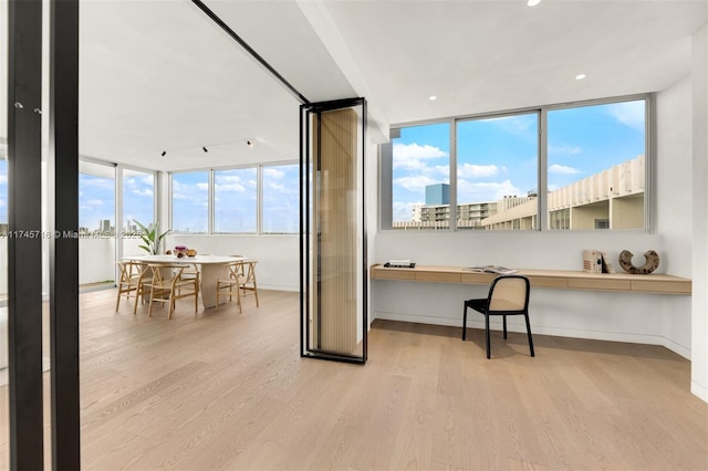 home office with built in desk and light hardwood / wood-style flooring