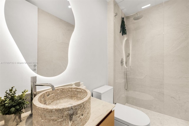 bathroom with vanity, tiled shower, and toilet