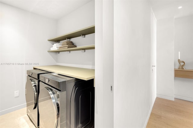 laundry area with light hardwood / wood-style floors and washer and dryer