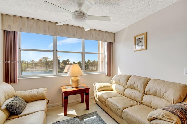 carpeted living room with ceiling fan, a textured ceiling, and a water view