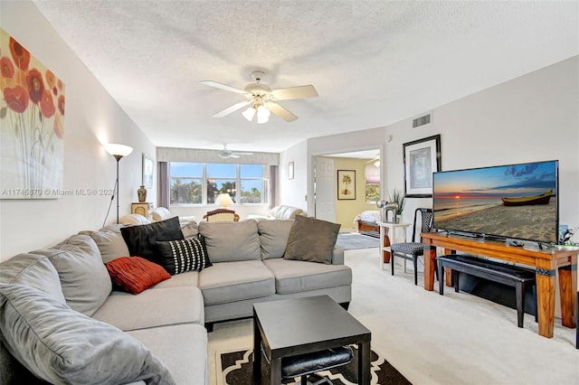 living room featuring ceiling fan, light colored carpet, and a textured ceiling