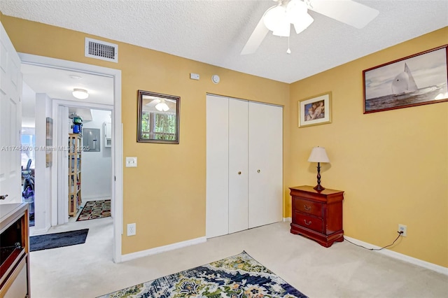 carpeted bedroom featuring ceiling fan, a closet, and a textured ceiling