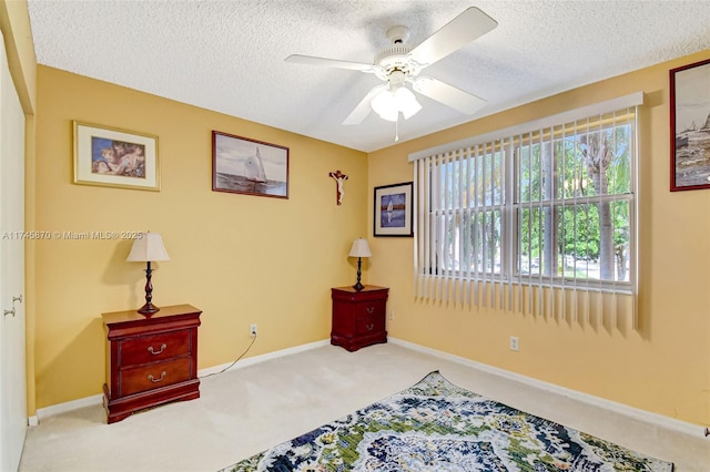 living area with ceiling fan, light carpet, and a textured ceiling