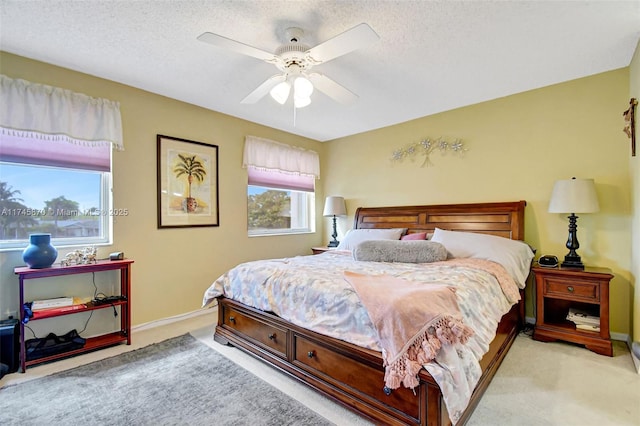 carpeted bedroom with ceiling fan and a textured ceiling