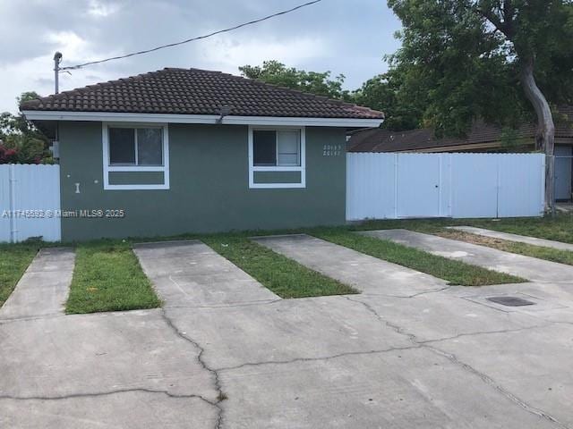 view of side of property with a tile roof, fence, and stucco siding