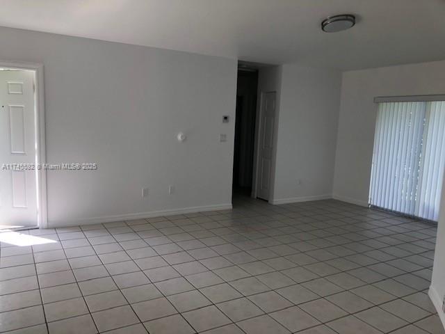 empty room featuring light tile patterned floors and baseboards