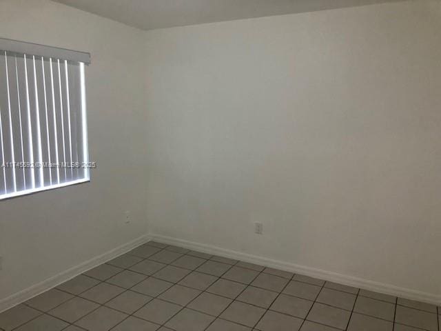 spare room with baseboards and light tile patterned floors