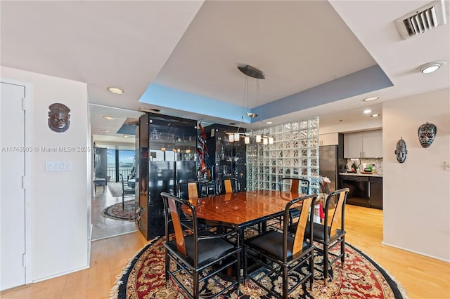 dining space featuring light hardwood / wood-style flooring and a raised ceiling