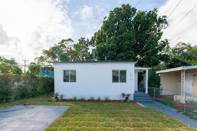 view of front of property featuring stucco siding, a front lawn, and fence