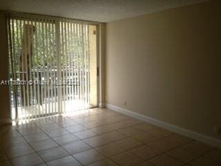 unfurnished room with tile patterned flooring and a wall of windows