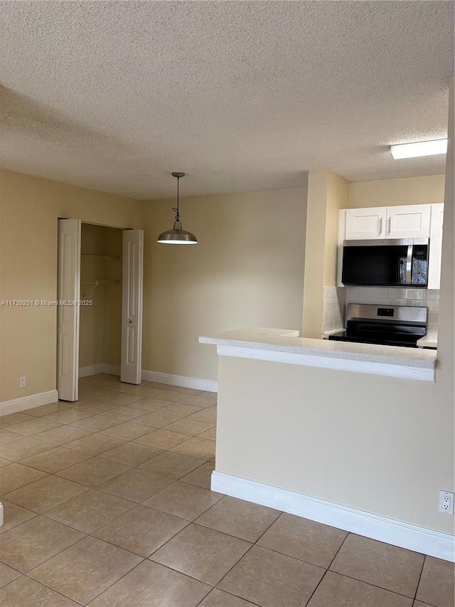 10717 Cleary Blvd Unit 203, Plantation, FL 33324 - kitchen featuring baseboards, white cabinets, light tile patterned floors, and appliances with stainless steel finishes