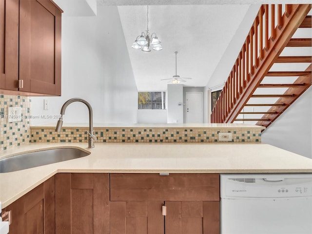 kitchen featuring sink, decorative light fixtures, vaulted ceiling, white dishwasher, and backsplash