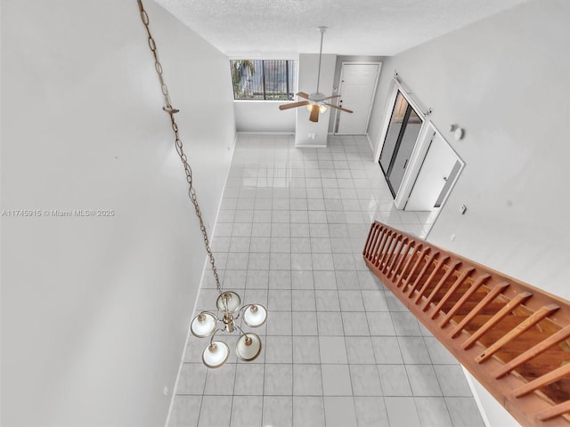 stairs featuring ceiling fan with notable chandelier, tile patterned floors, and a textured ceiling