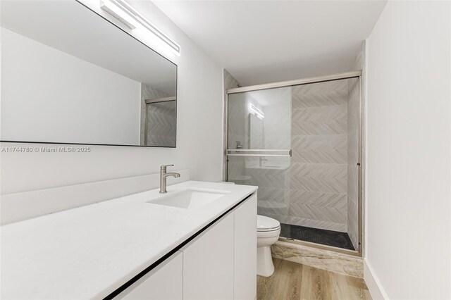 full bathroom with a shower stall, wood finished floors, toilet, and vanity
