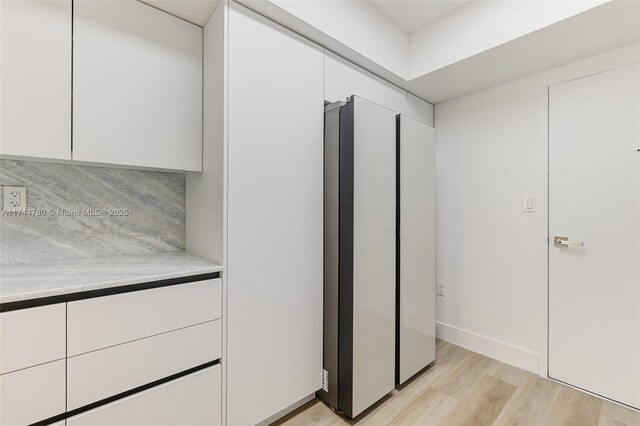 kitchen featuring white cabinets, light countertops, tasteful backsplash, and light wood finished floors