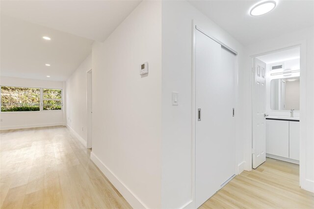 hall with baseboards, visible vents, light wood-style flooring, and recessed lighting