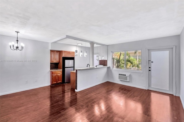 kitchen featuring hanging light fixtures, dark wood-type flooring, stainless steel fridge, and kitchen peninsula